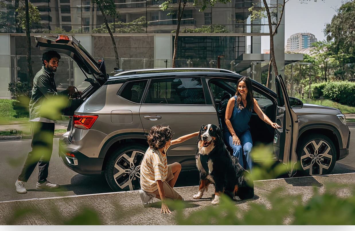 A family and their dog beside their car on a city street